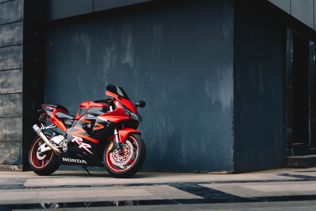 photo of red and black honda sport bike parked next to black 2317519 1024x683 - Opony motocyklowe - kompendium wiedzy